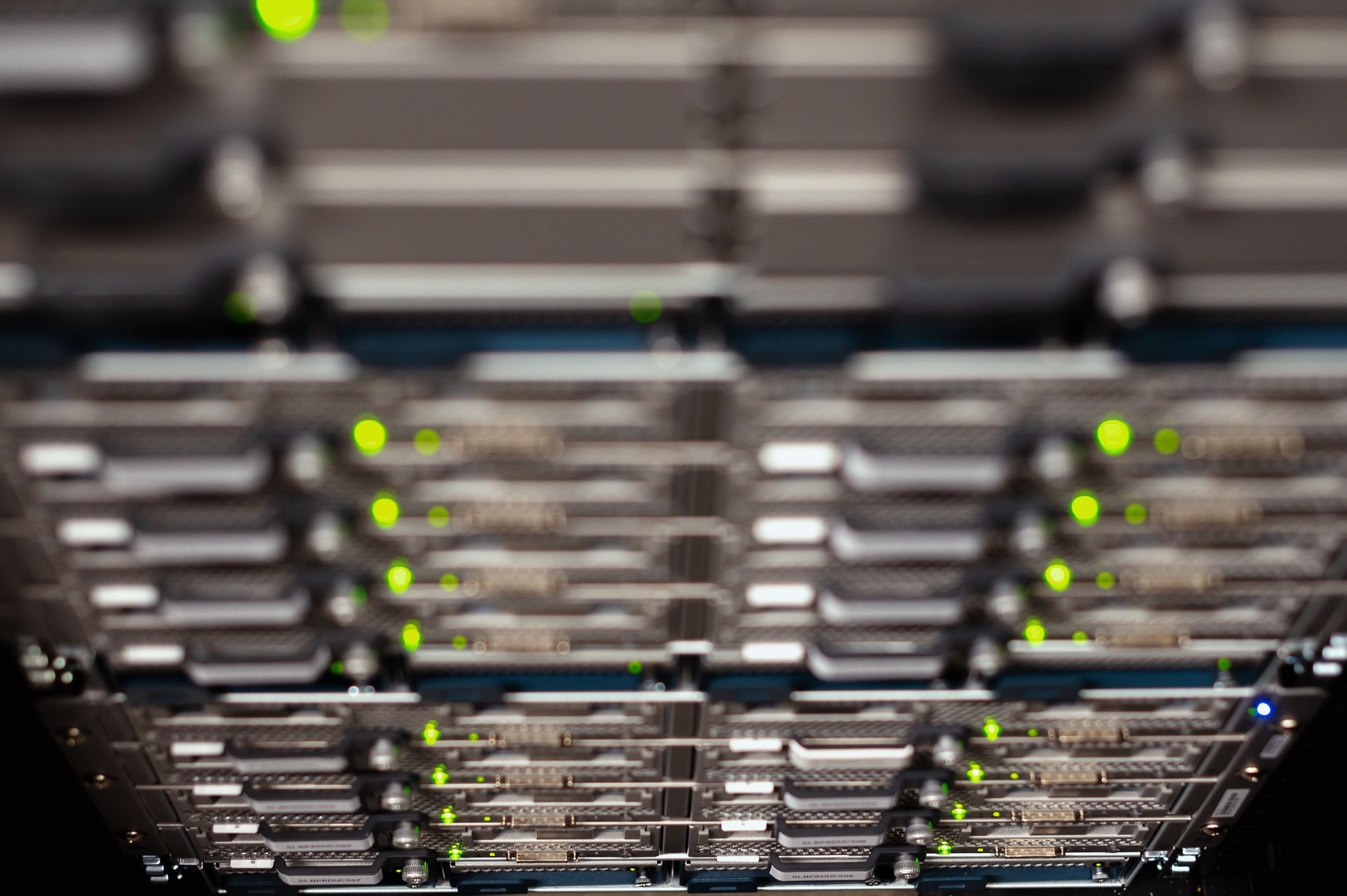 Dettaglio ravvicinato di server impilati in un armadio, con le spie verdi accese