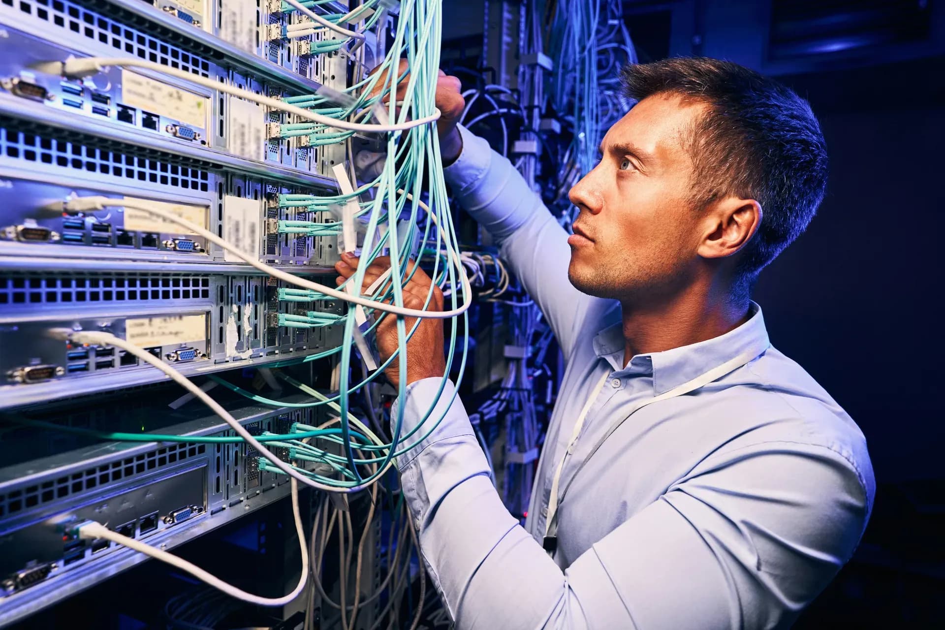 Tecnico che collega i cavi di rete su un armadio di switch