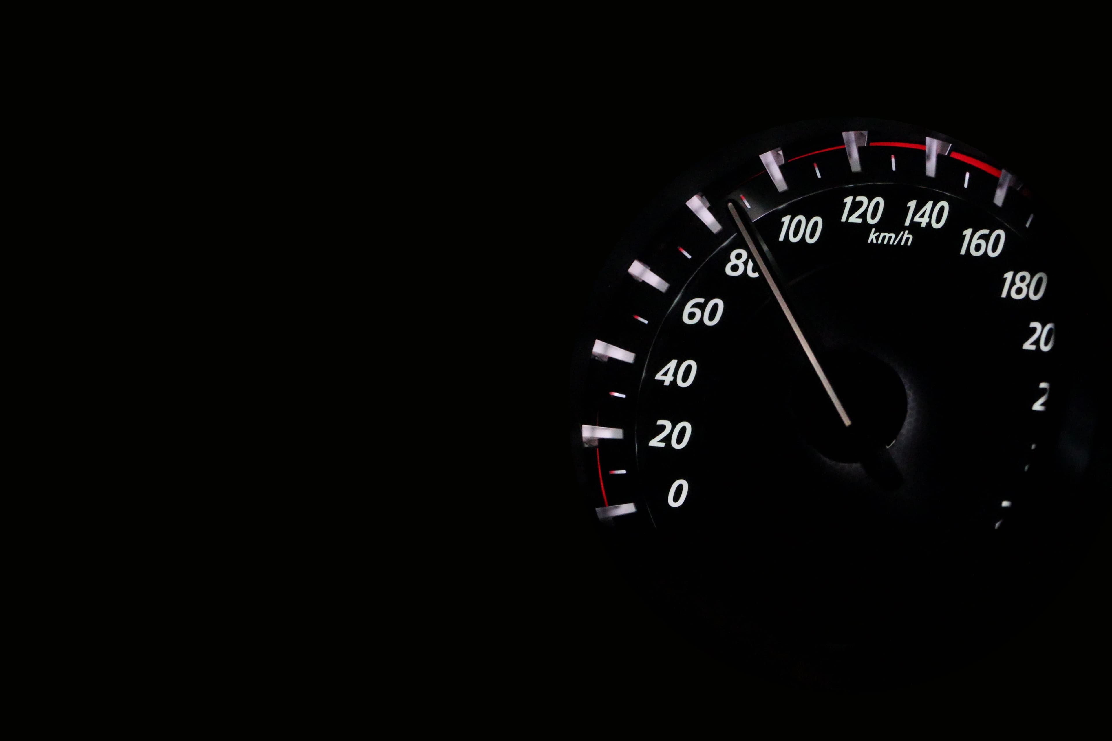 Contachilometri di un’auto illuminato nel buio, con la lancetta sopra i 100 km/h